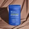 Opakowanie naturalnego suplementu BICAPS B Complex na odporność oraz redukcję zmęczenia chronicznego na tle brązowej tkaniny