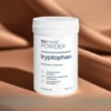 Biały proszek L-Tryptofanu Powder Tryptophan - czysty aminokwas w formie proszku z miarką umożliwiającą precyzyjne odmierzenie porcji 350 mg, w białym opakowaniu na tle brązowej tkaniny