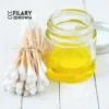 Butelka oleju dla dzieci Zielony Olej, dostępna w atrakcyjnej cenie, otoczona pałeczkami do uszu.