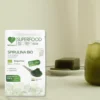Opakowanie spiruliny na stole, a obok szklanka z koktajlem ze spiruliny