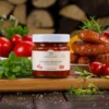 Słoik łagodnego keczupu z naturalnych składników na tle kiełbasy